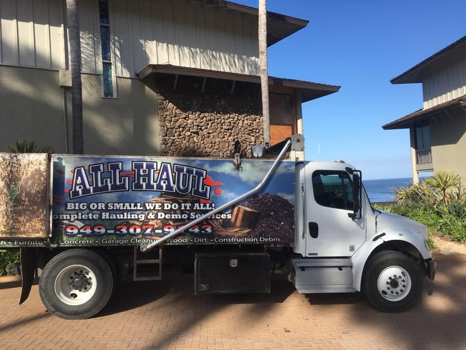 All Haul truck parked near the coast, hillside property in the background