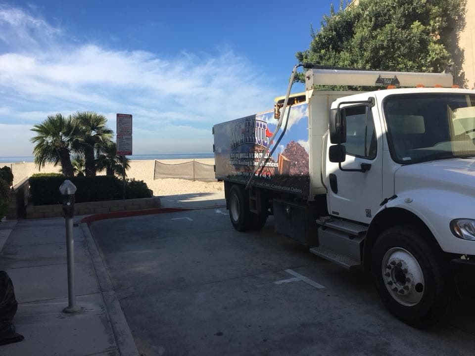 All Haul truck parked near the beach, palm trees in the background