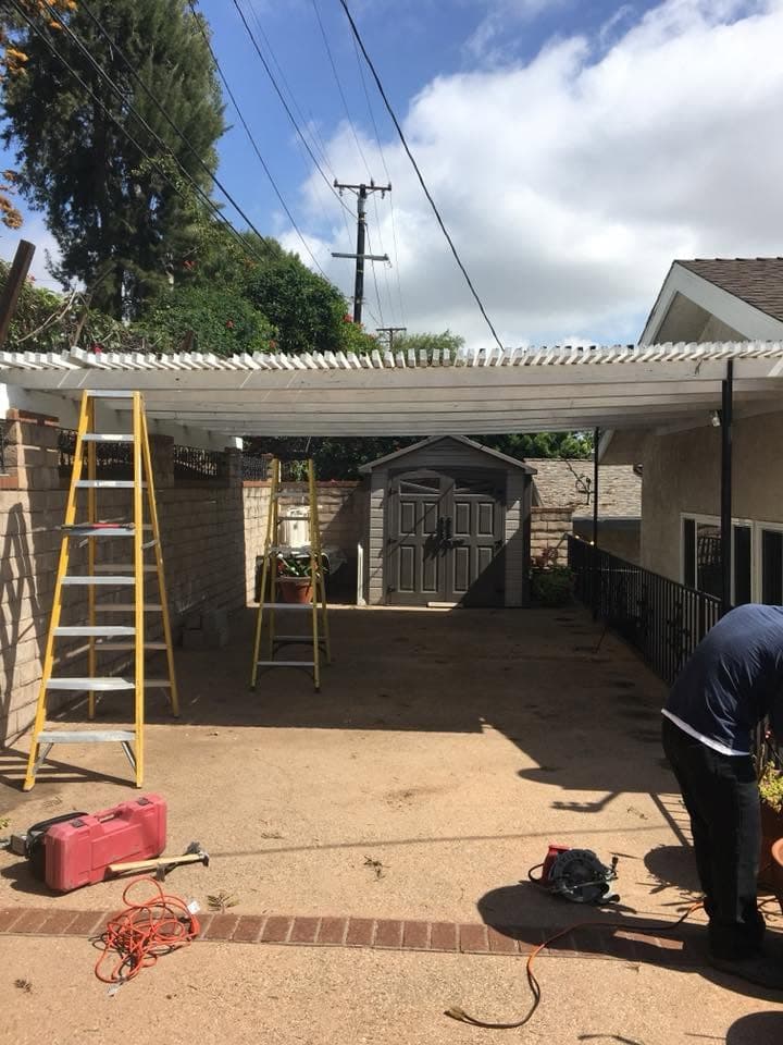 Crew removing an old patio cover, ladders set up in the backyard