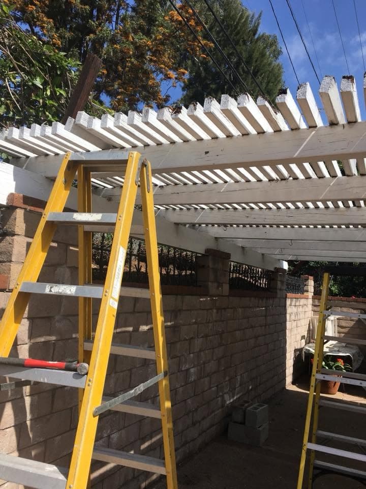 Worker on a ladder removing patio cover slats