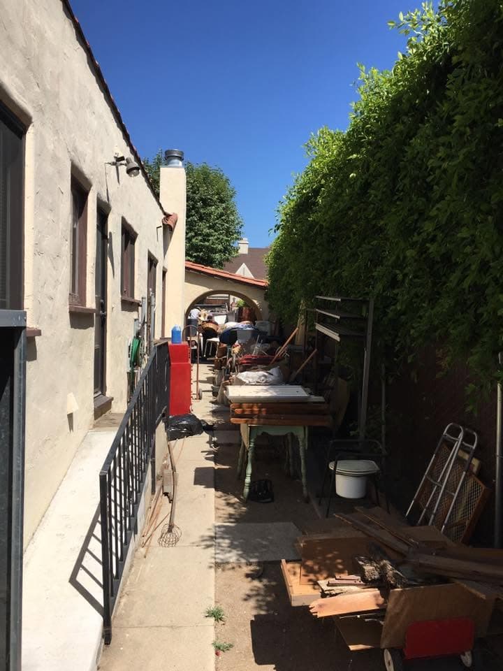 Furniture and belongings staged in an alley for pickup