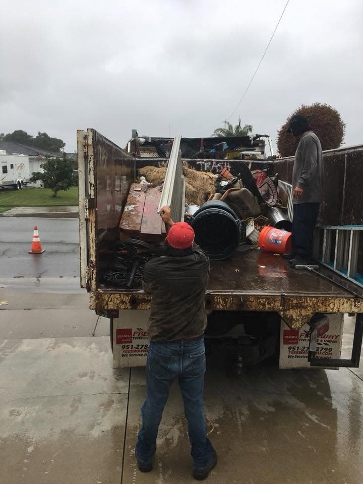 Crew loading old furniture and debris into the truck in the rain